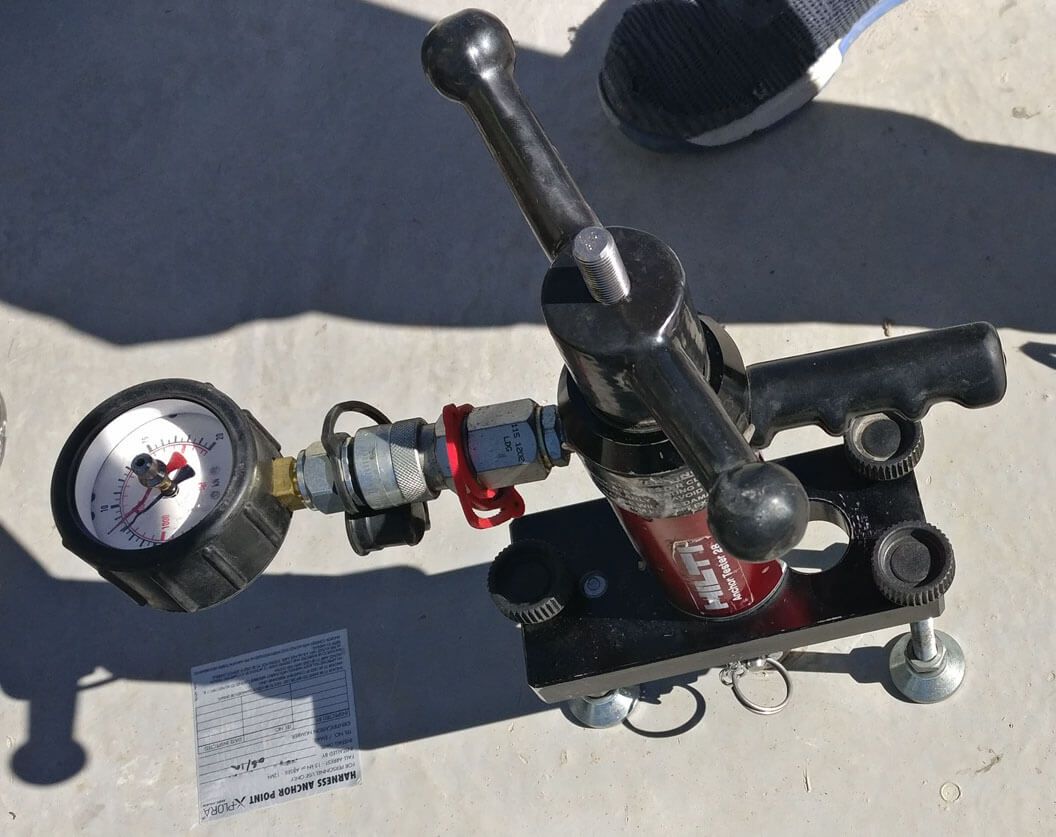 Metal ladder with safety cage attached to a white wall against a blue sky.