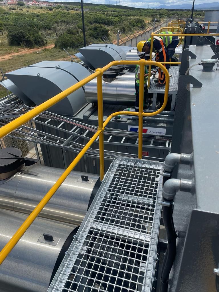 Yellow handrails on industrial structure with workers, exterior setting.