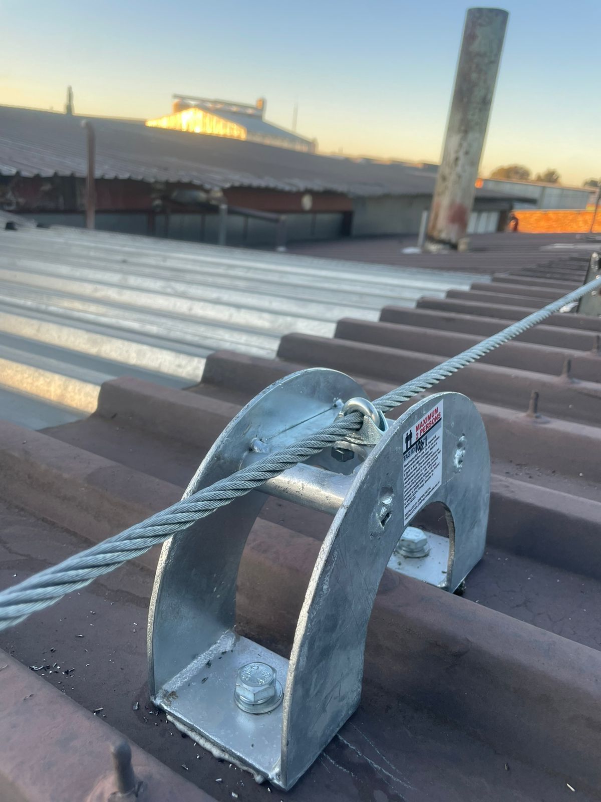Safety cable system on a corrugated metal roof. A metal bracket holds the cable.