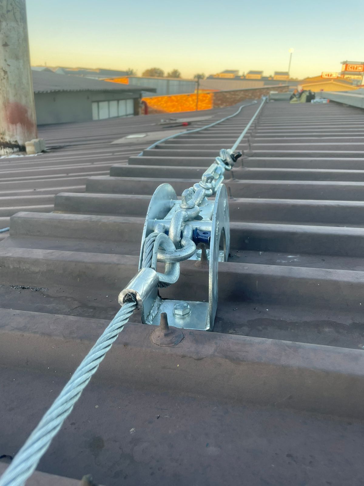 Steel cable lifeline system installed on a corrugated roof.