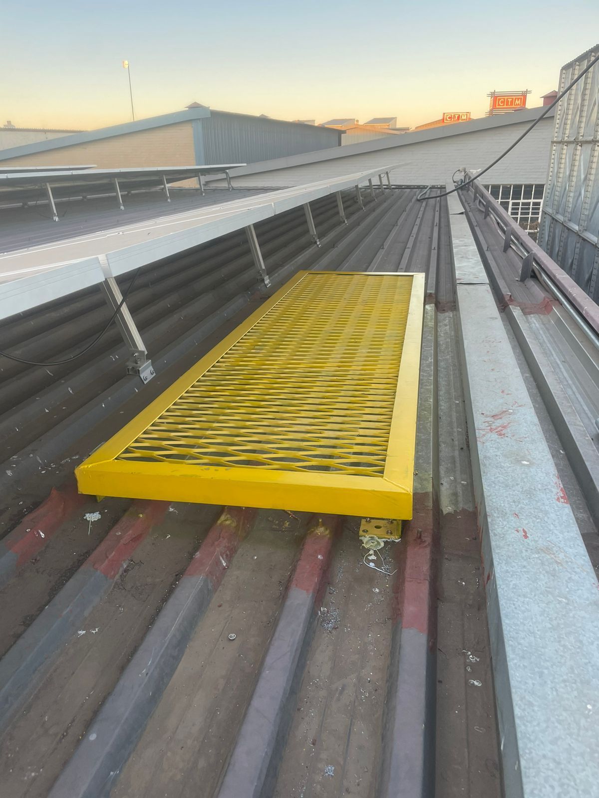 Yellow rectangular platform on a corrugated metal roof, likely a safety feature.
