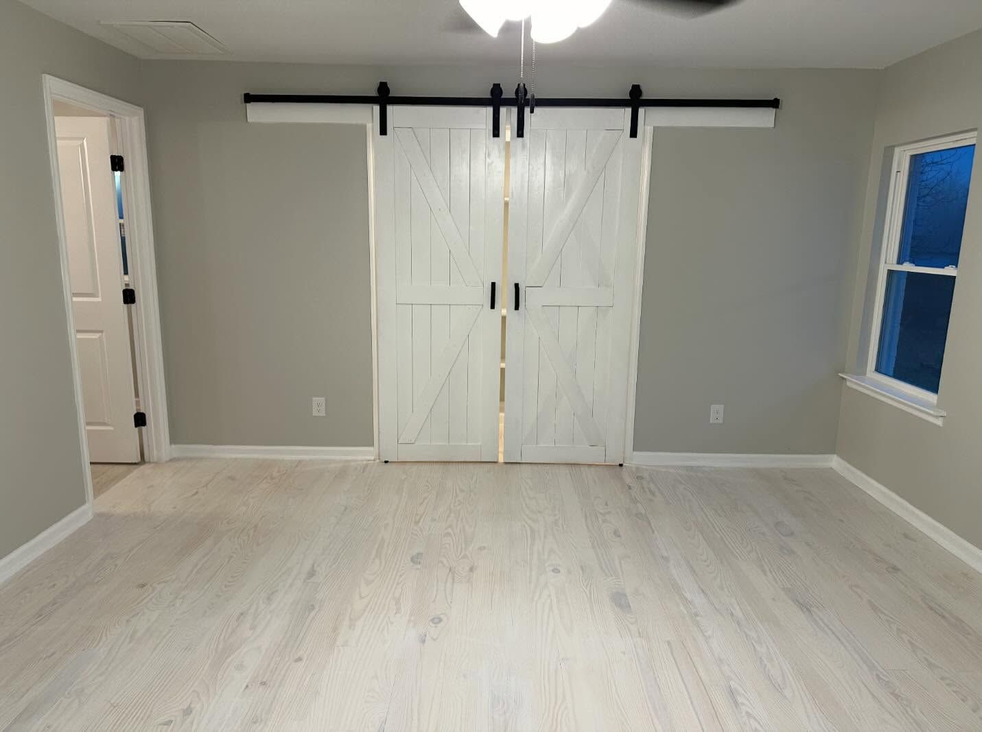 Bedroom with wood flooring, green accent wall, bed, and TV on a table by a window.
