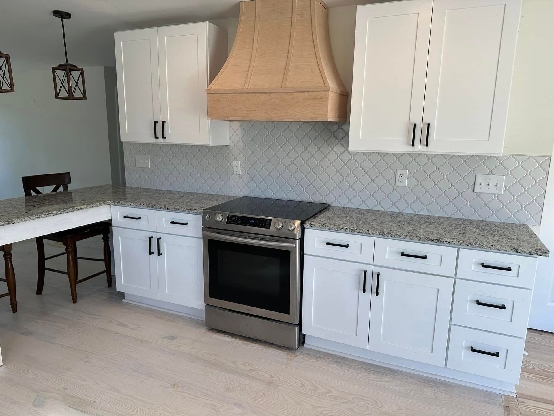 Modern kitchen with wood and white cabinetry, a black range, and a dining area.