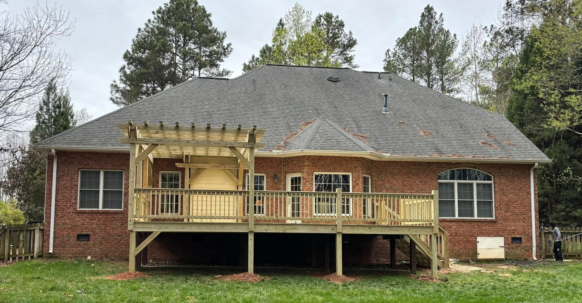 Deck of a house overlooking a lake, featuring a curved wall, glass doors, and decorative railing.