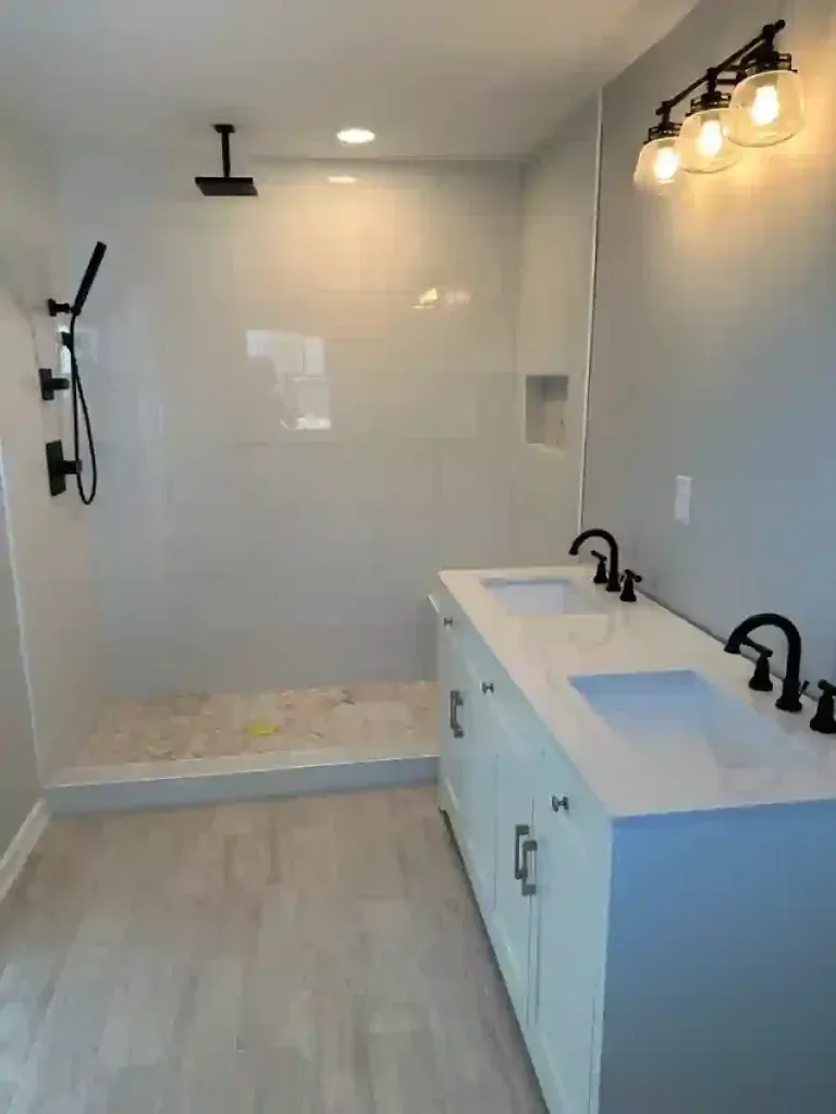 Bathroom with white vanity, black fixtures, and a walk-in shower with light gray tiles.
