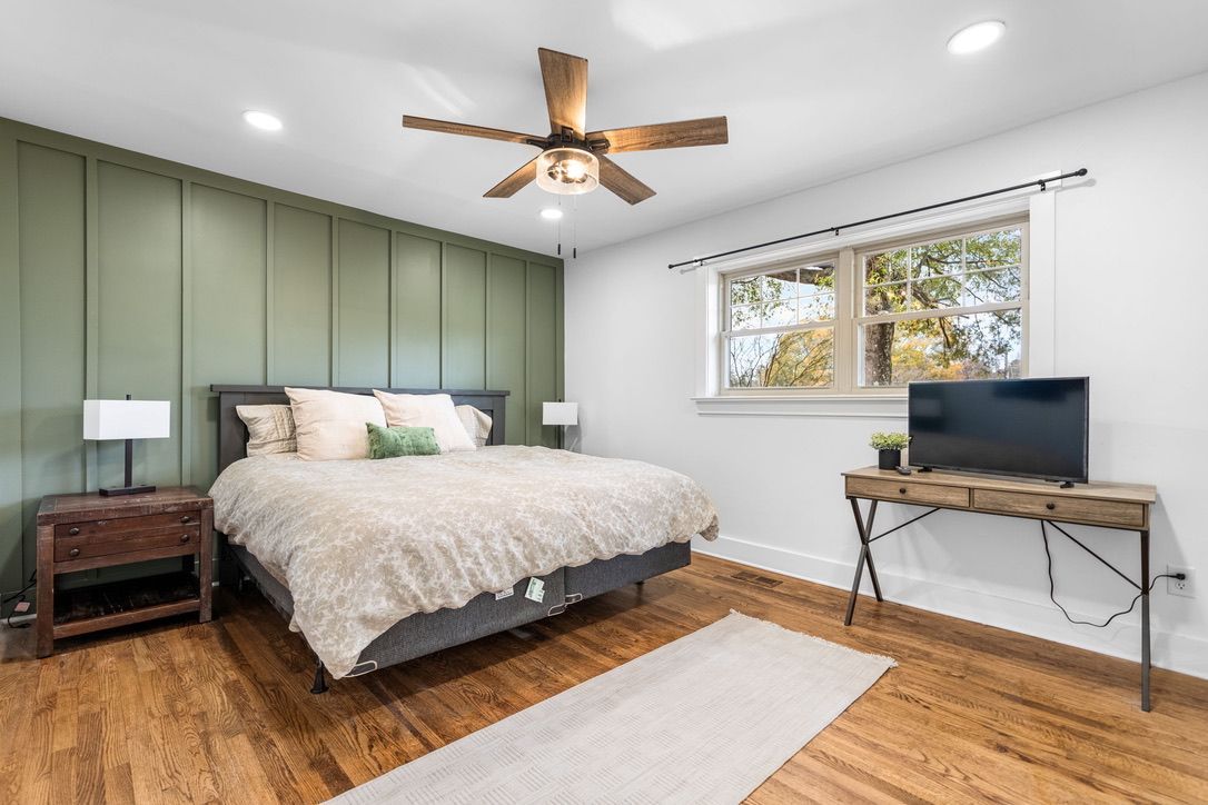 Person patching a wall inside a room with a wooden ceiling and window. Tools and materials are on the floor.