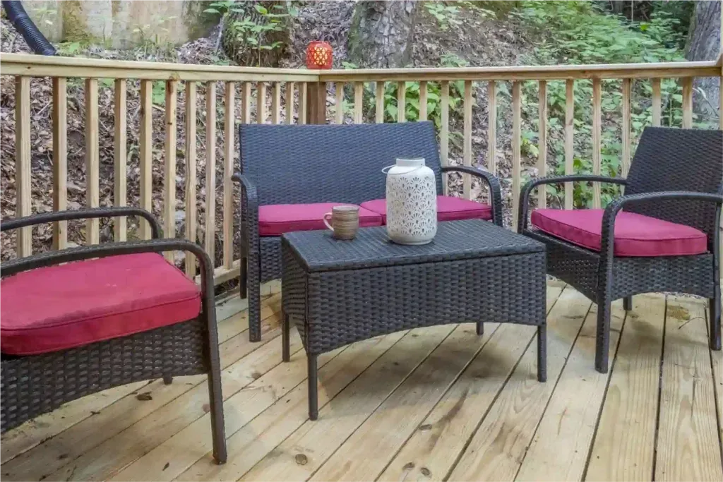 Outdoor deck with wicker furniture and red cushions.