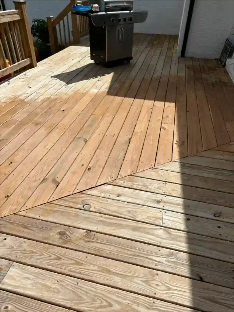 Wooden deck with a gas grill, featuring sun and shadow patterns.