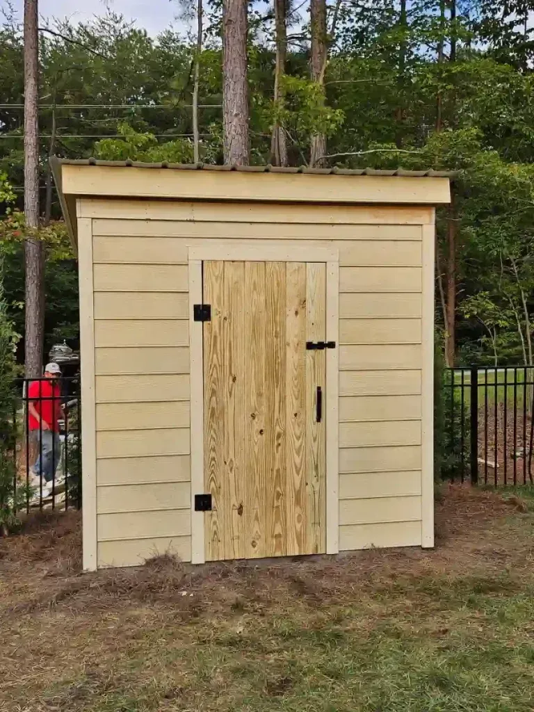 Yellow shed with a wooden door in a yard.
