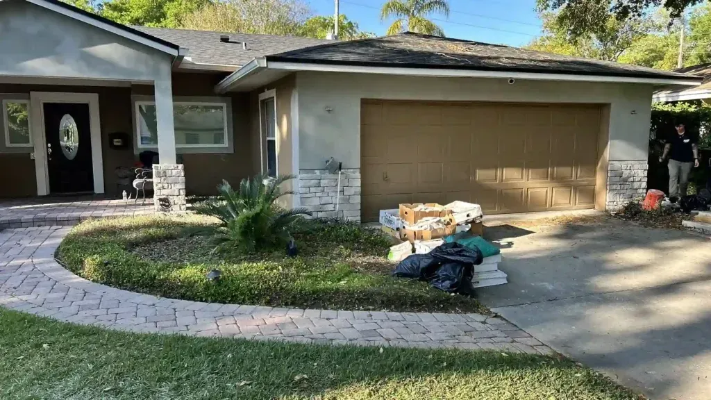 House with brown garage door, light brown stucco exterior, and landscaping with a brick pathway.