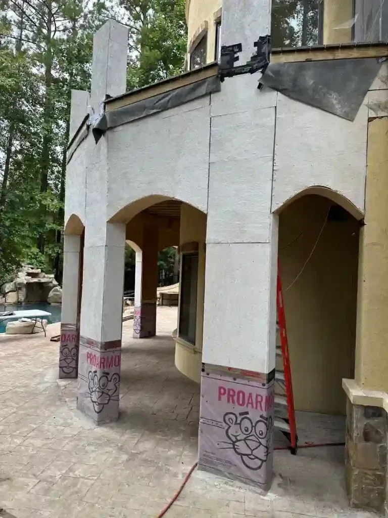 Outdoor structure under construction: arched supports with foam insulation, red ladder, and swimming pool visible.