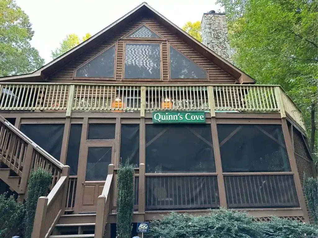 A two-story cabin with a screened-in porch, balcony, and 