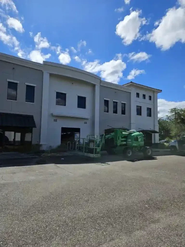 Beige stucco building with arched entryways and black trim.