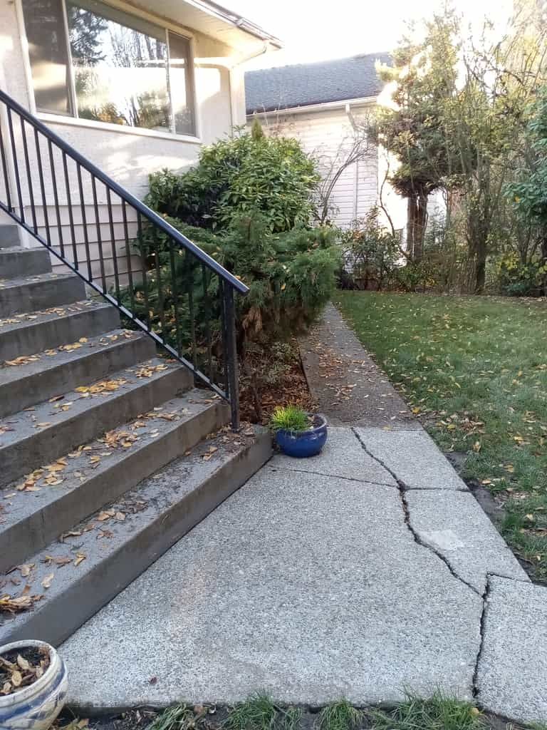 a cement sidewalk with a planter on the side of it