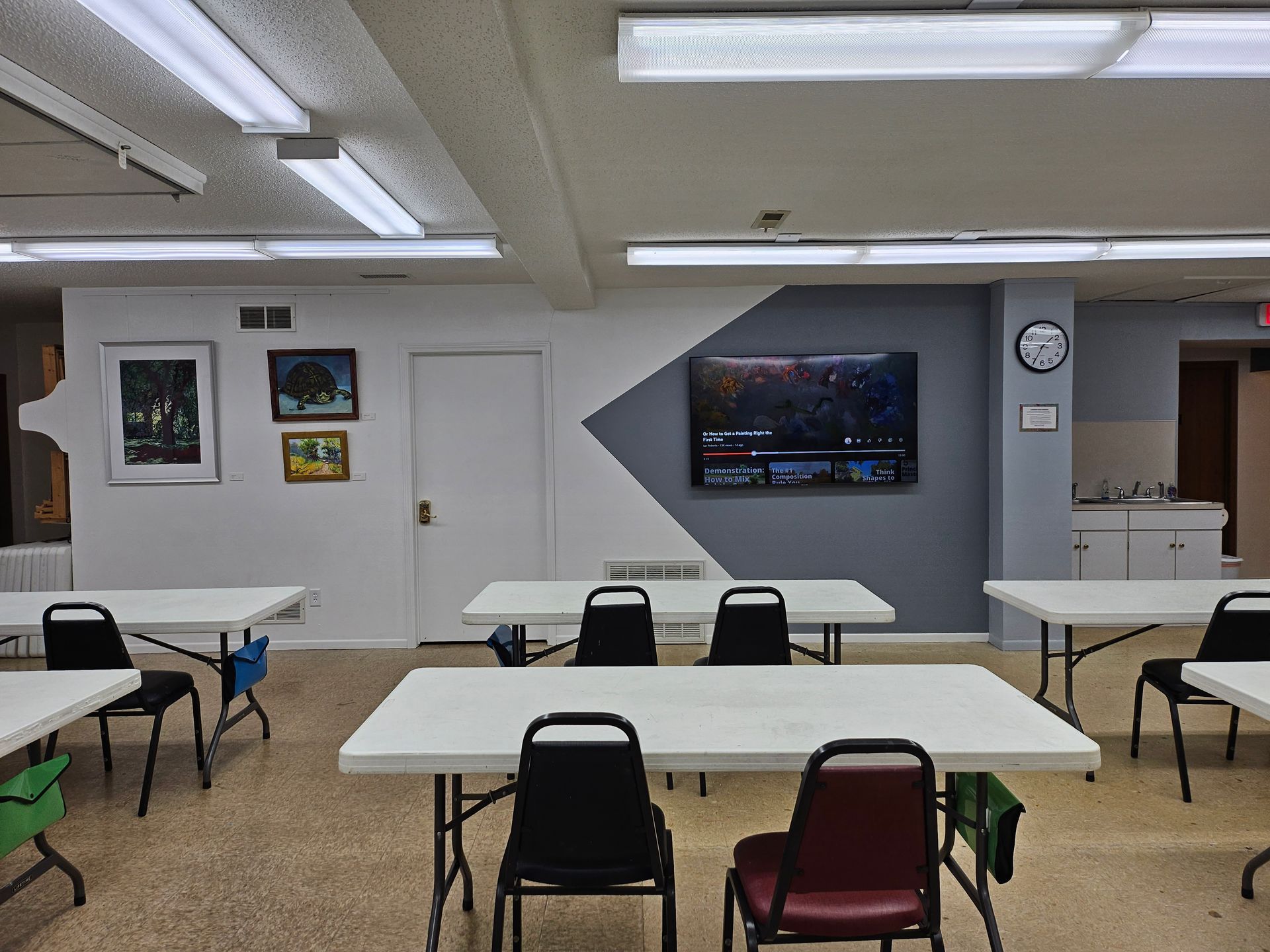 A room with tables and chairs and a clock on the wall