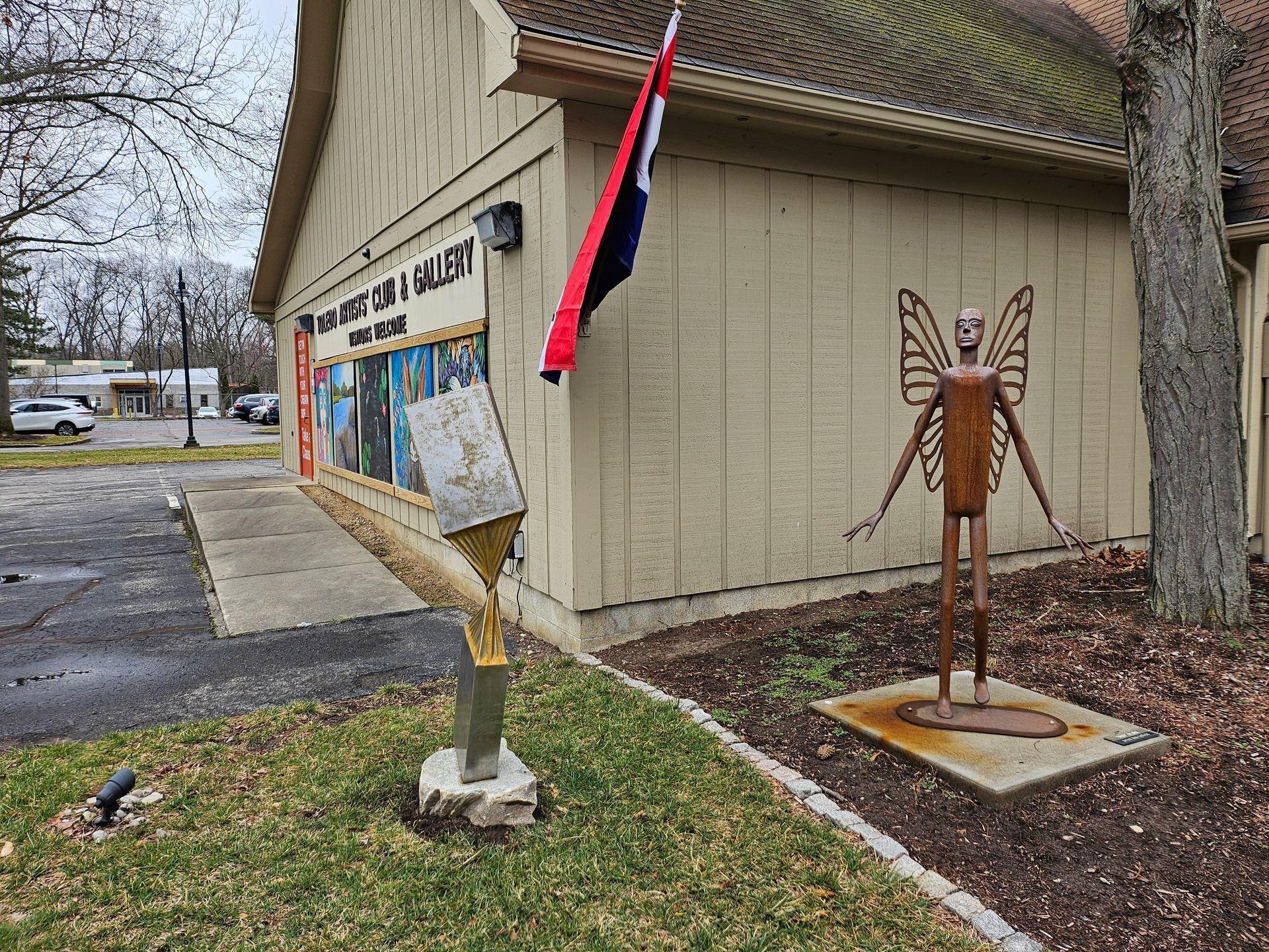 A statue of a butterfly is in front of a building.