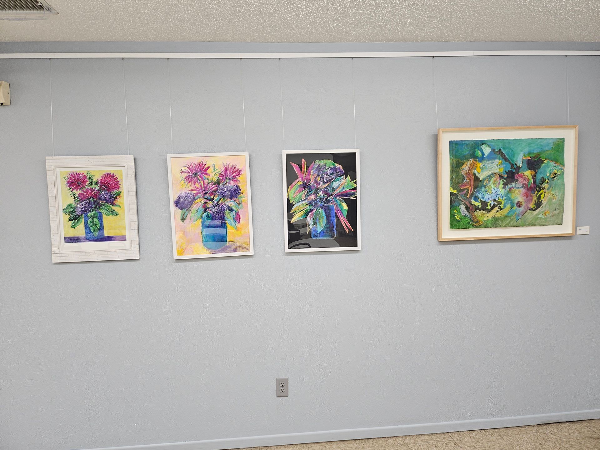 Three paintings are hanging on a wall in a room