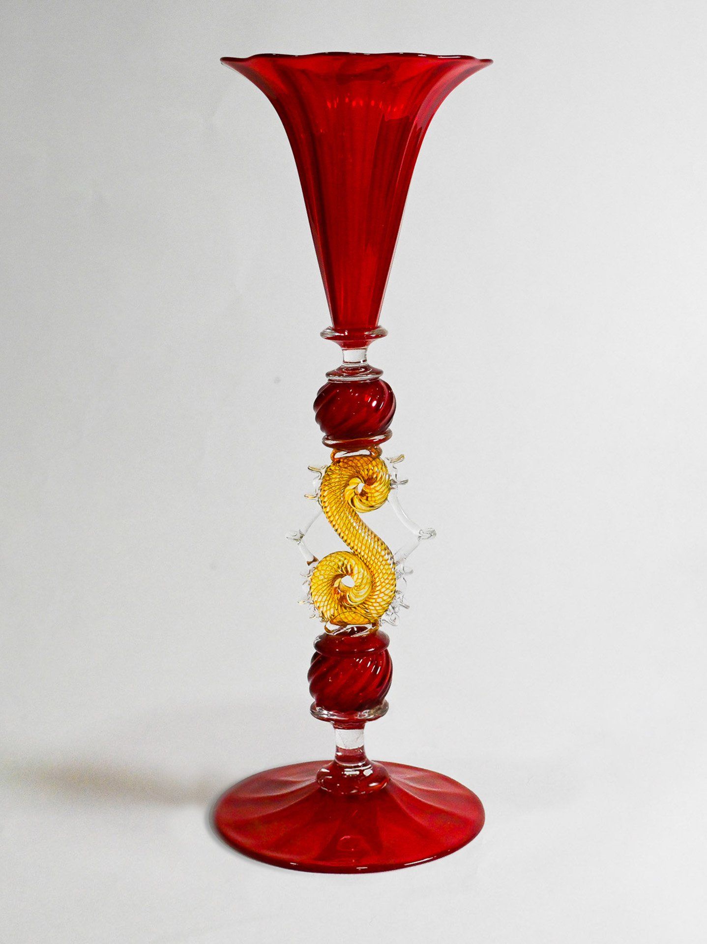 A red wine glass with a yellow swirl on the base