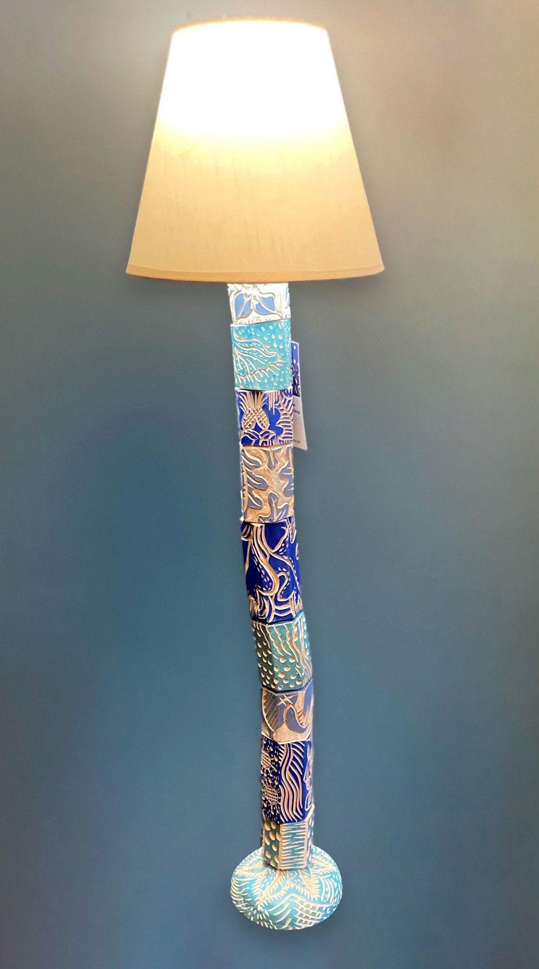 A blue and white lamp with a white shade is hanging on a wall.