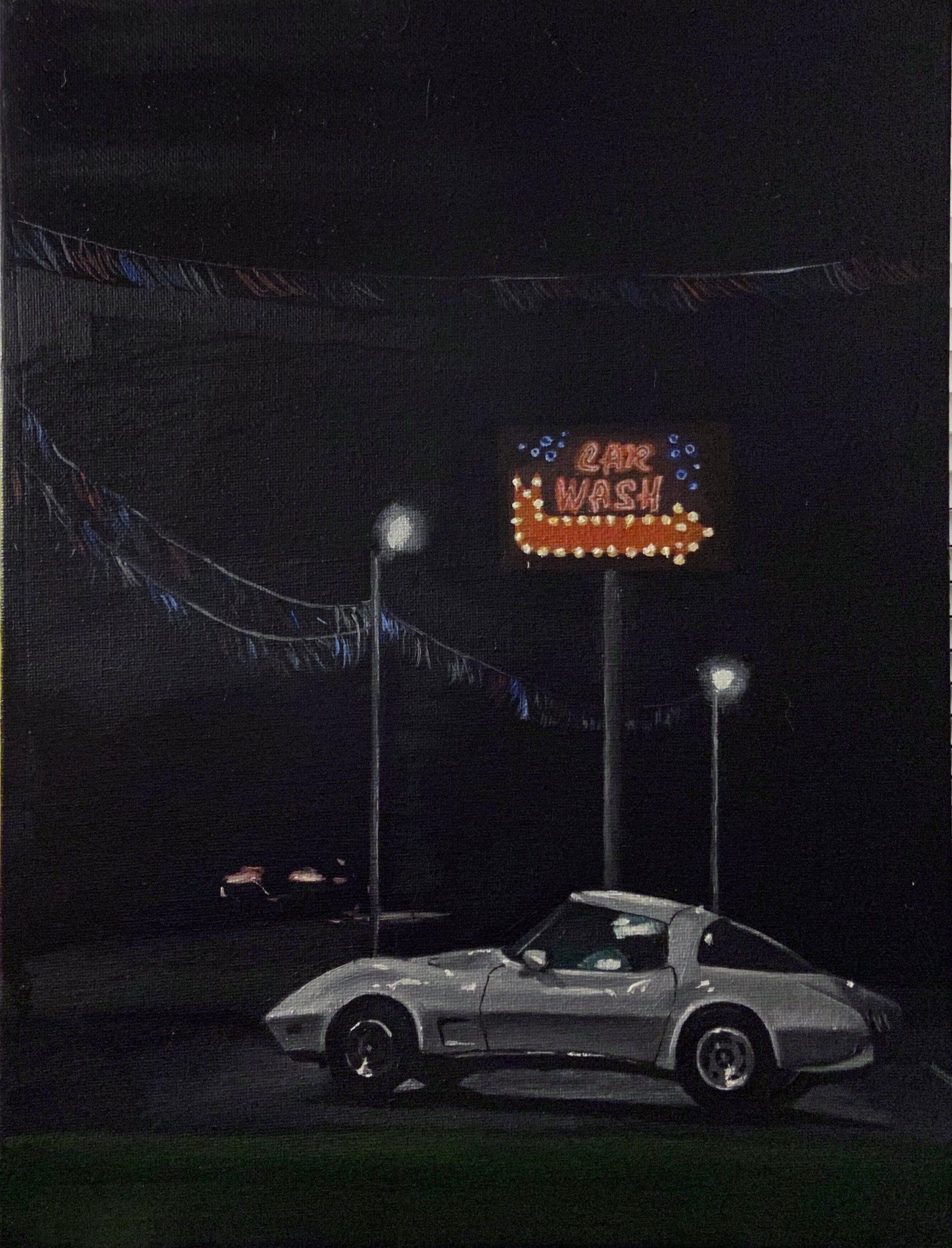 A car is parked in front of a car wash at night.