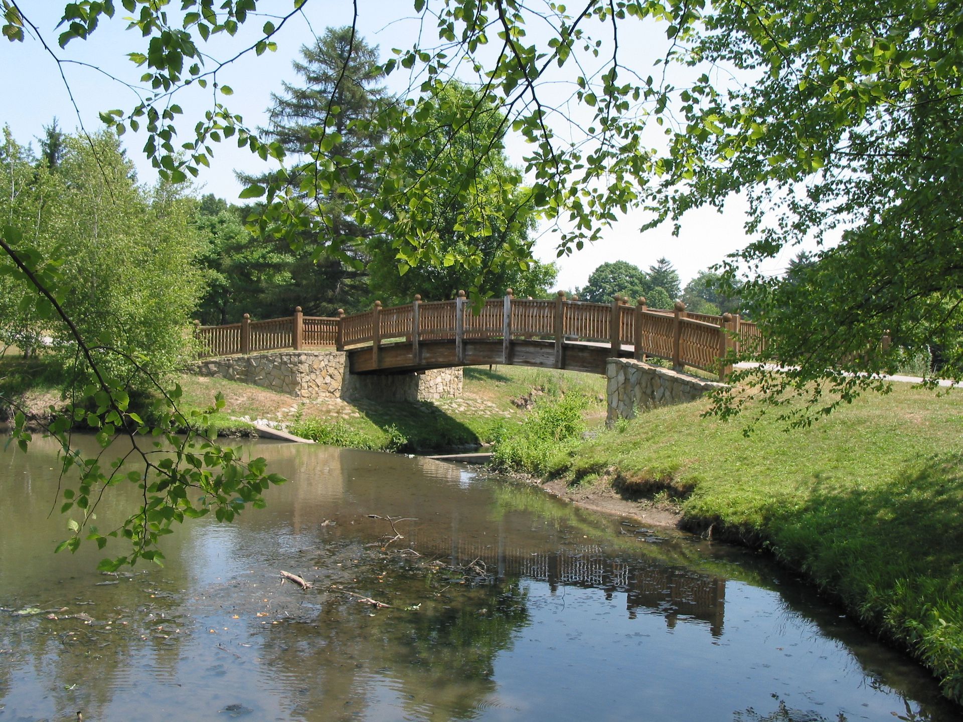 A wooden bridge over a river with trees in the background