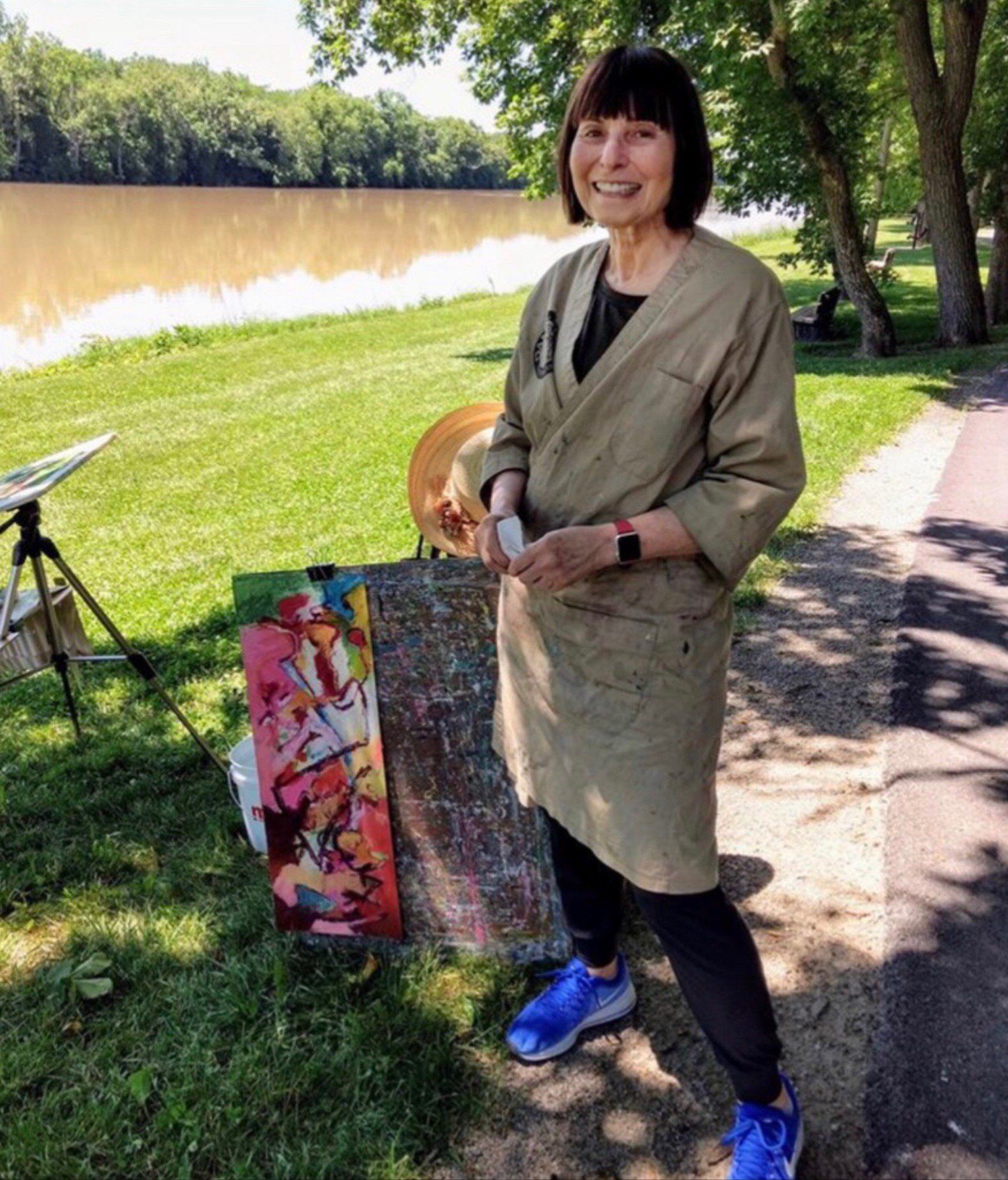 A woman is standing next to a painting in a park