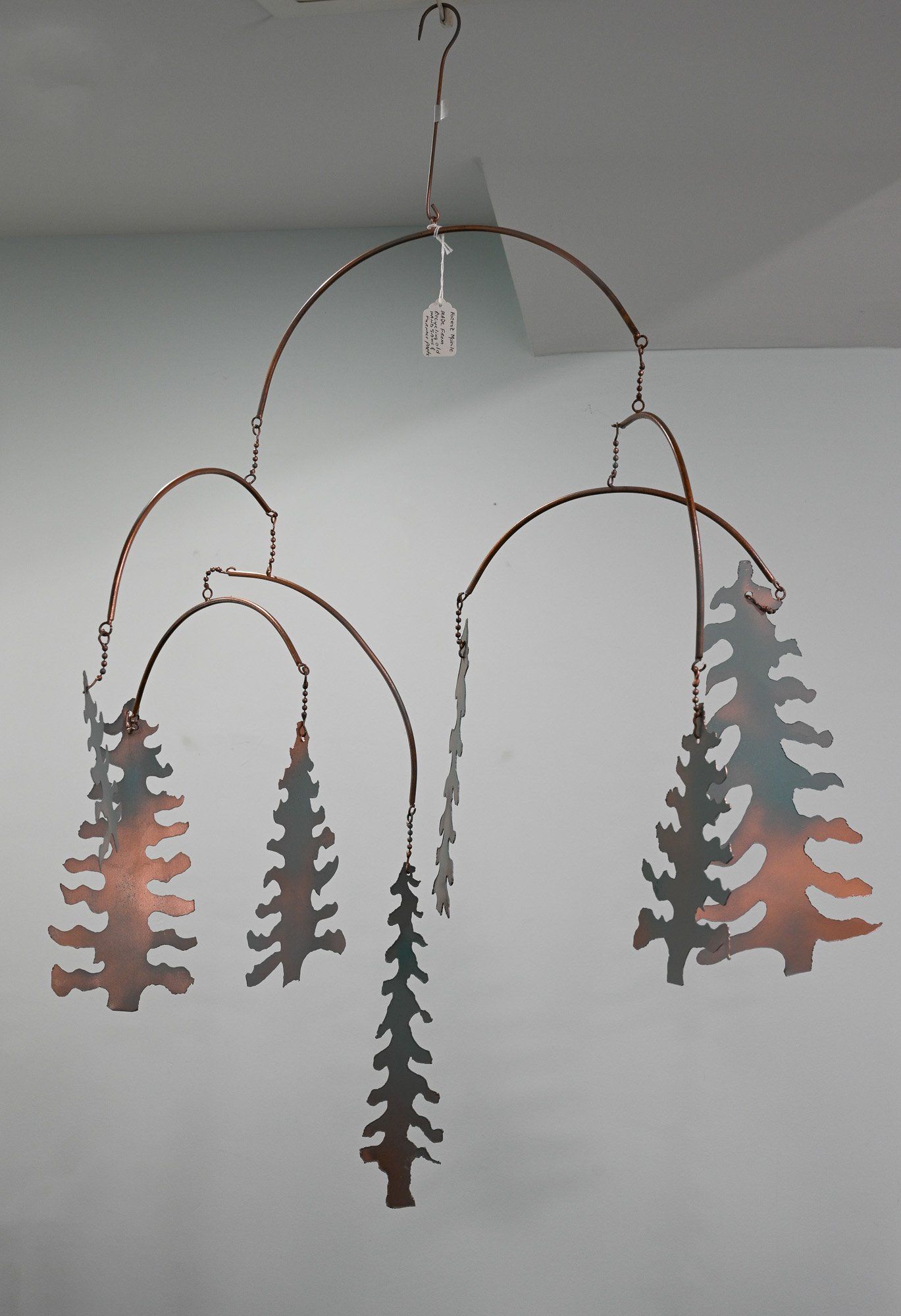 A mobile with trees on it is hanging from the ceiling
