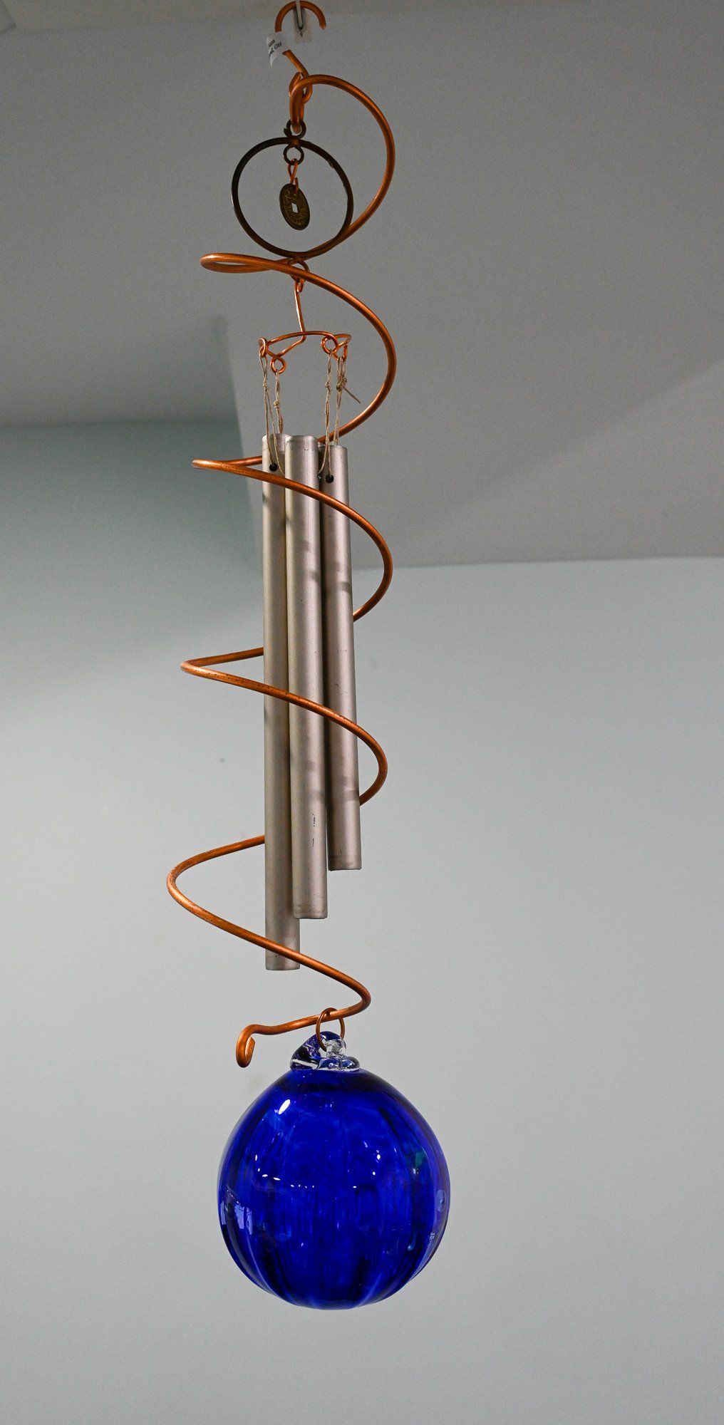 A wind chime with a blue ball hanging from the ceiling.