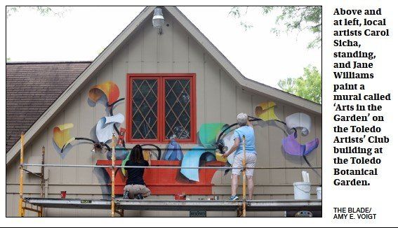 A mural is being painted on the side of a building