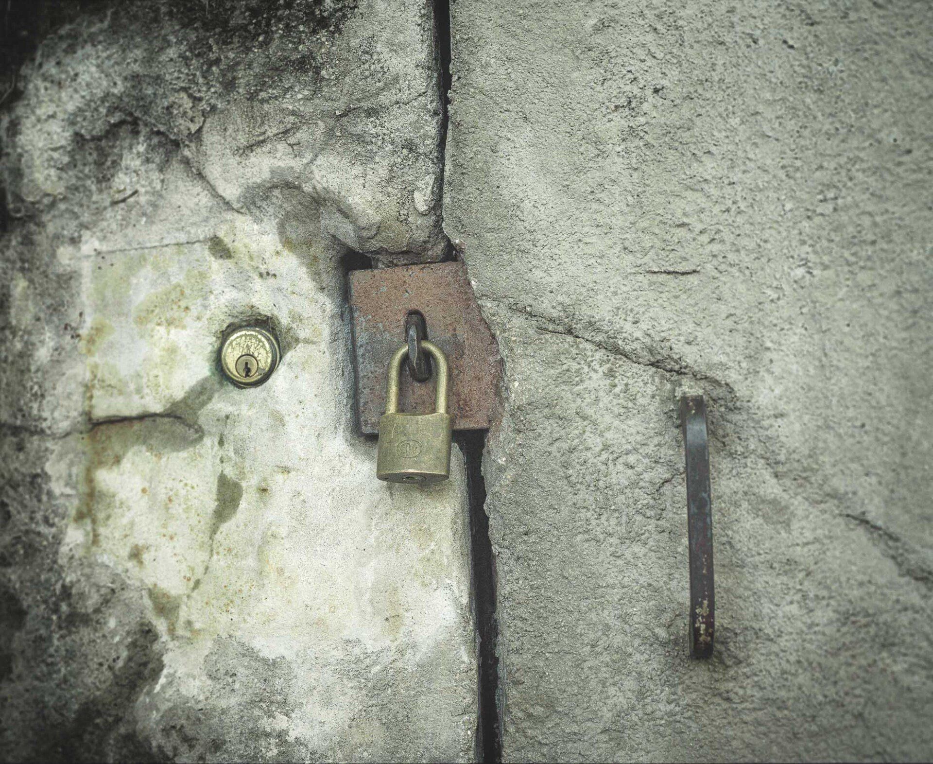A padlock is hanging on a concrete wall.