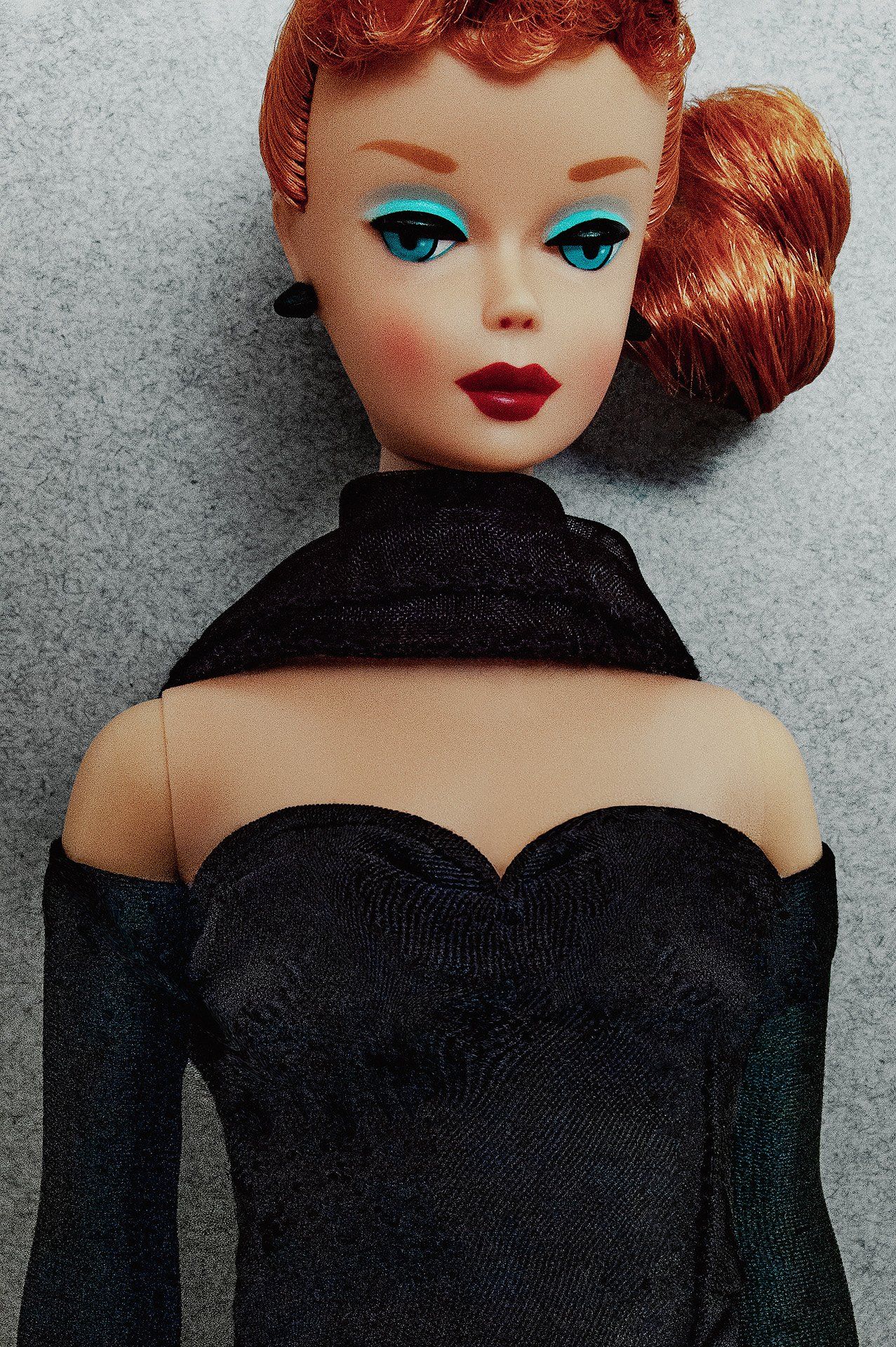 A close up of a barbie doll wearing a black dress