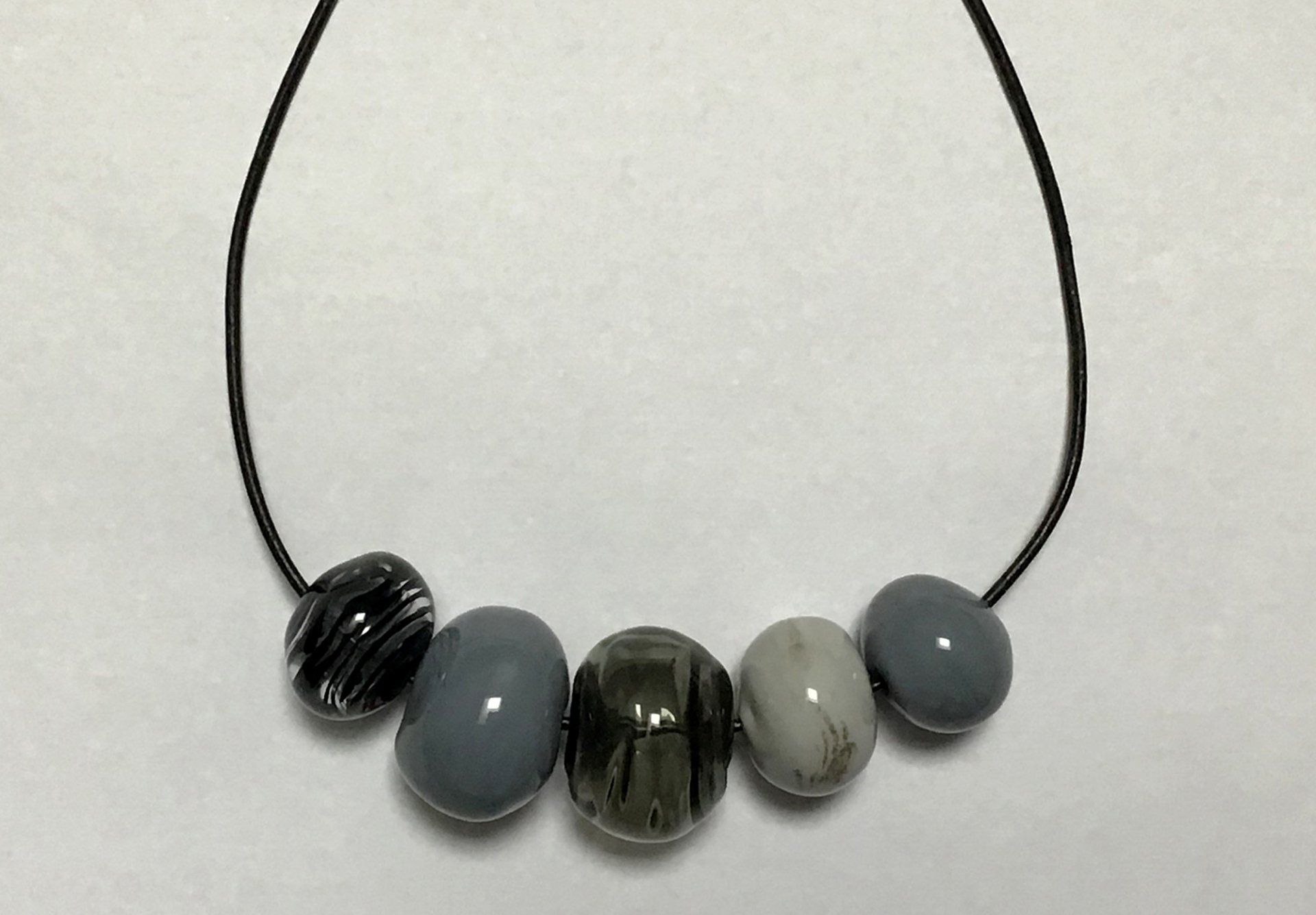 A necklace with gray and black beads on a black string