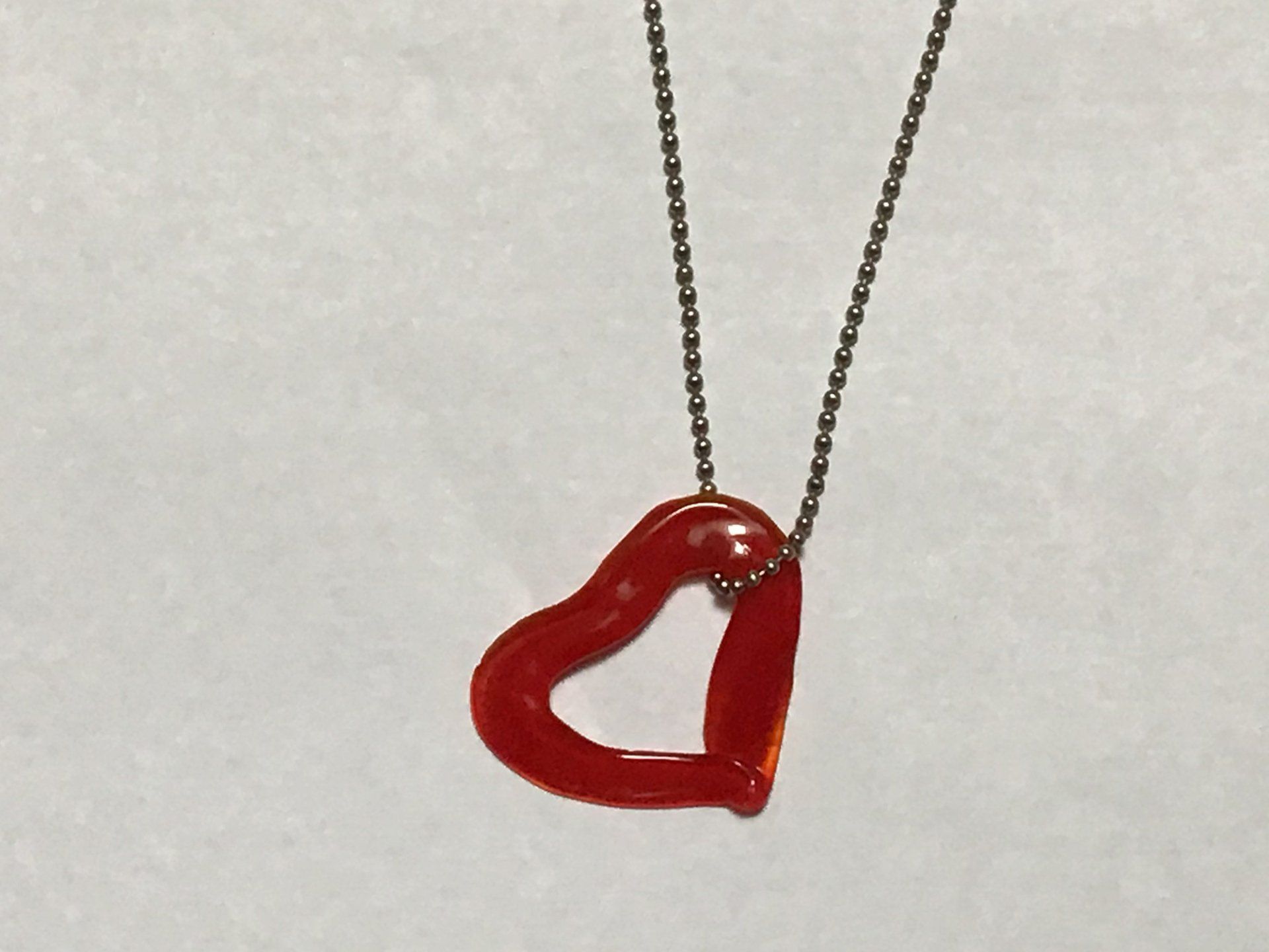 A necklace with a red heart shaped pendant on a chain
