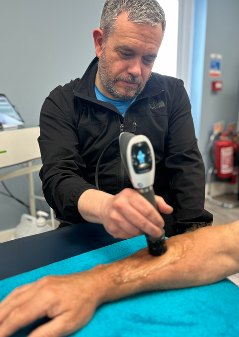 Martyn Glover - rehabilitation specialist using a shockwave machine on a clients arm