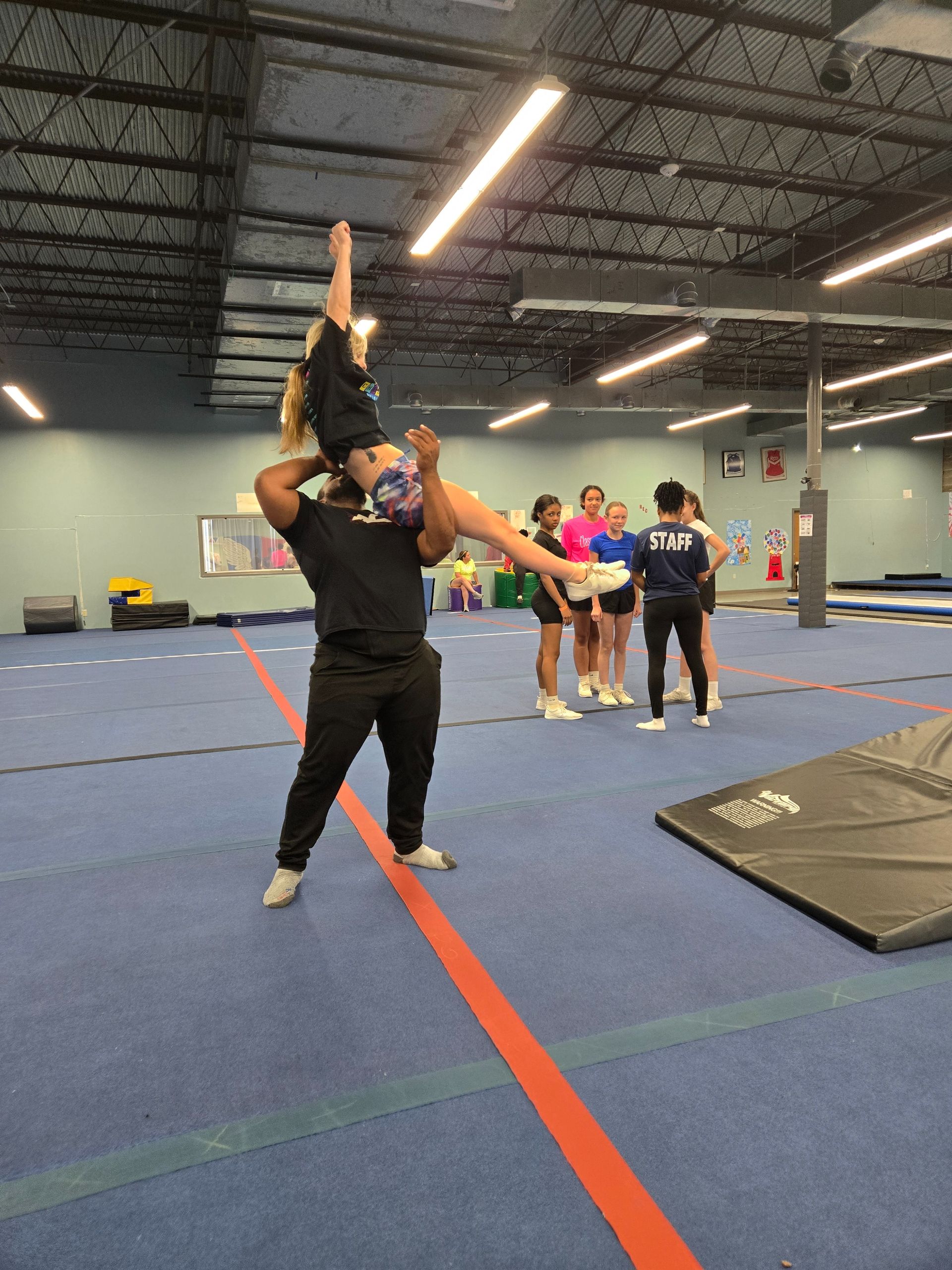 A man is doing a flip on a trampoline in a gym.