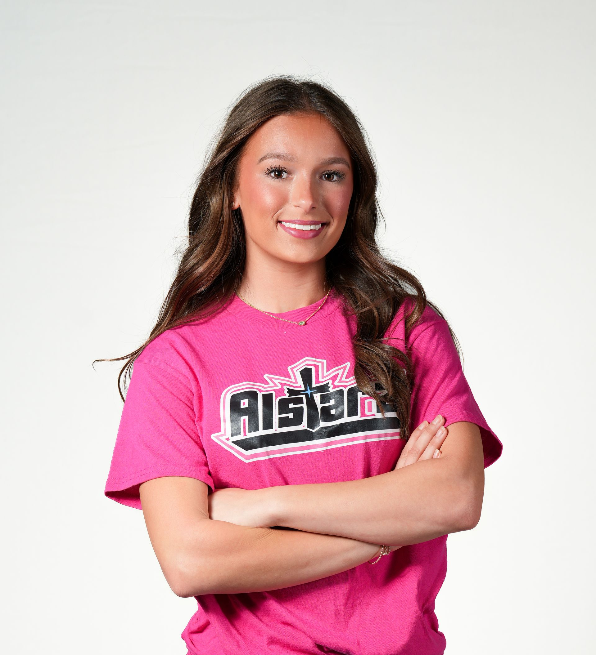 A cheerleader wearing a red top and skirt is standing with her hands on her hips.