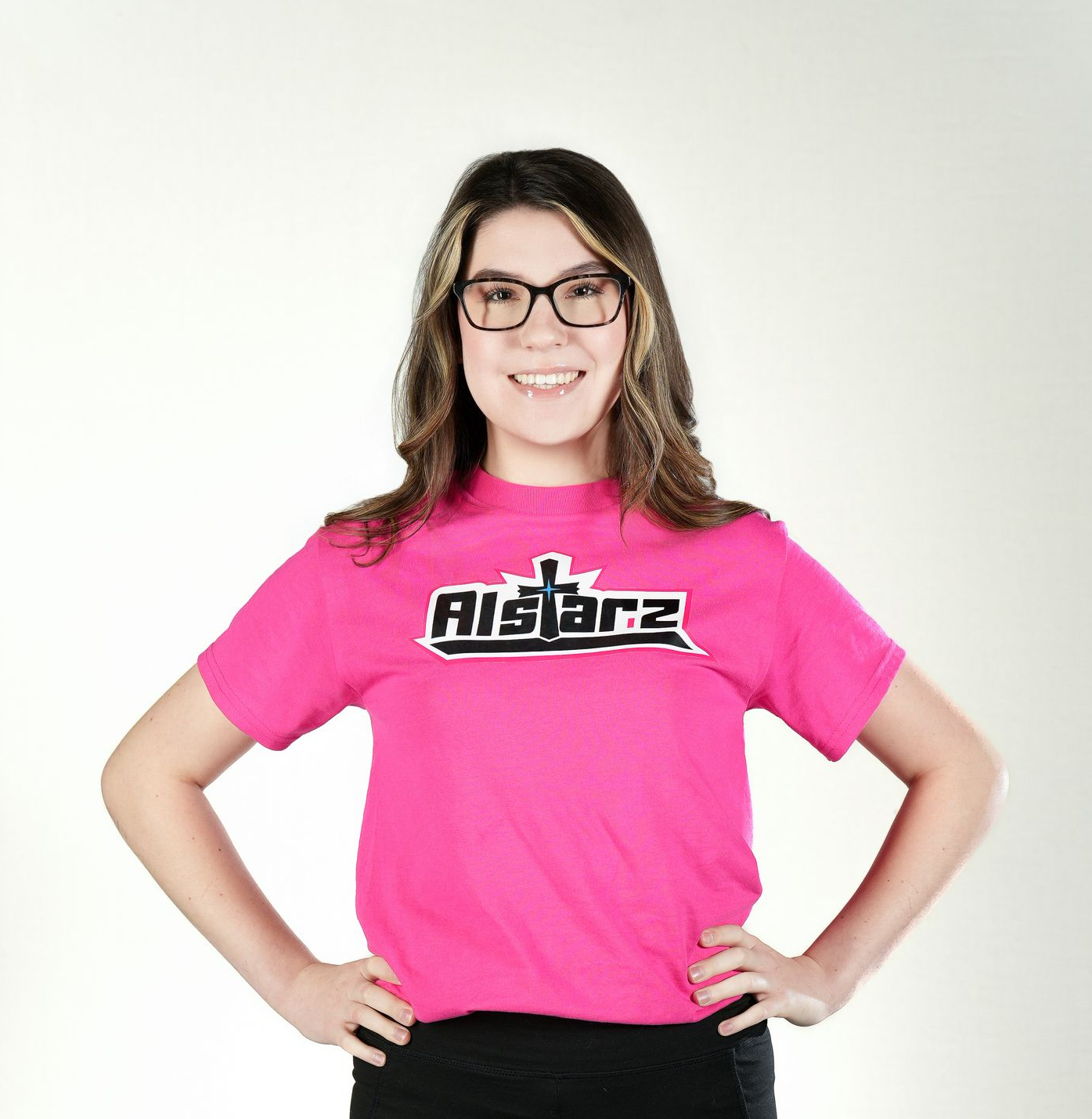 A woman wearing a blue aca t-shirt is standing with her hands on her hips.