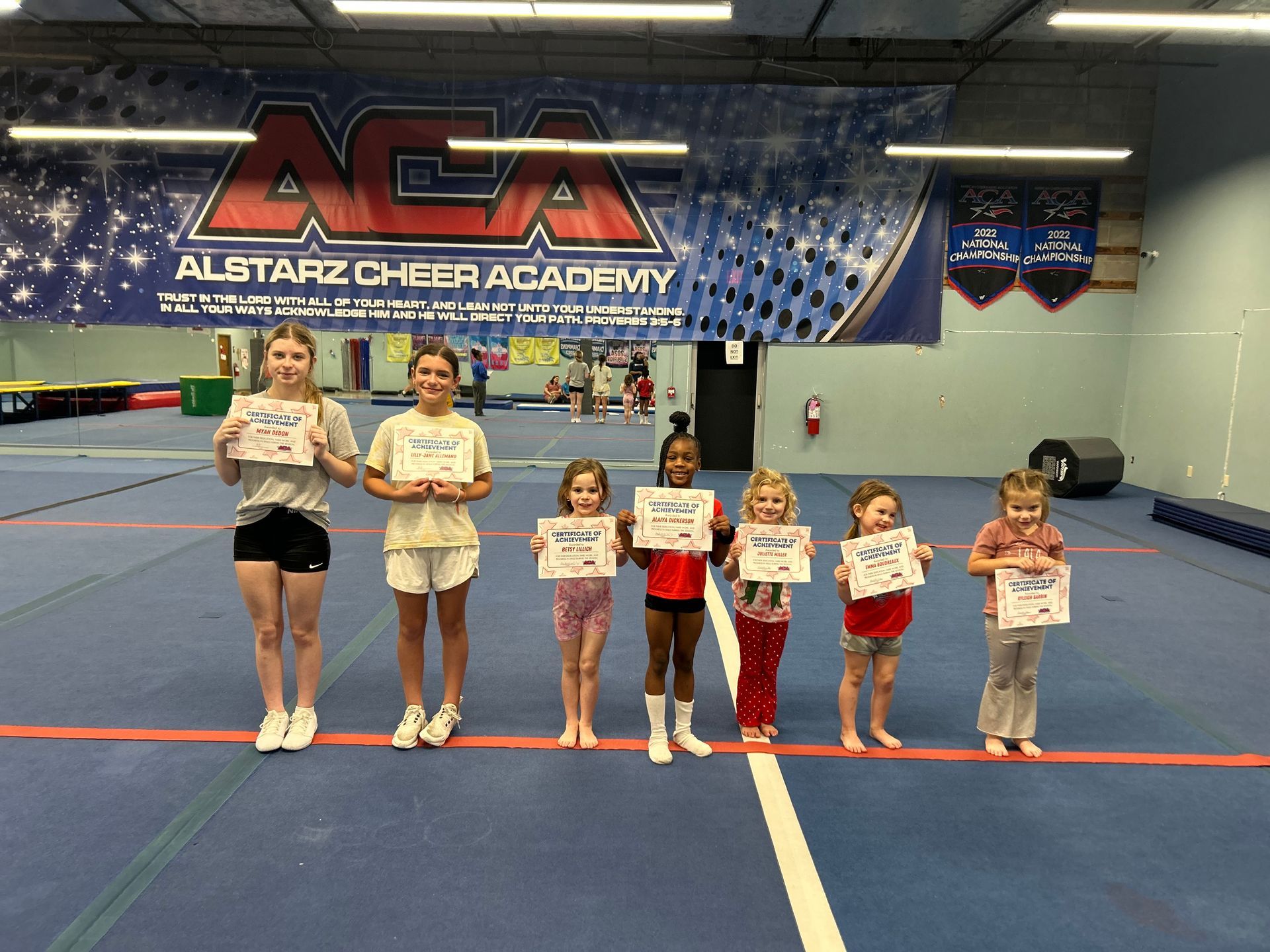 A group of young girls are holding certificates in a gym.
