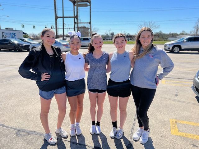 A group of girls are posing for a picture in a parking lot
