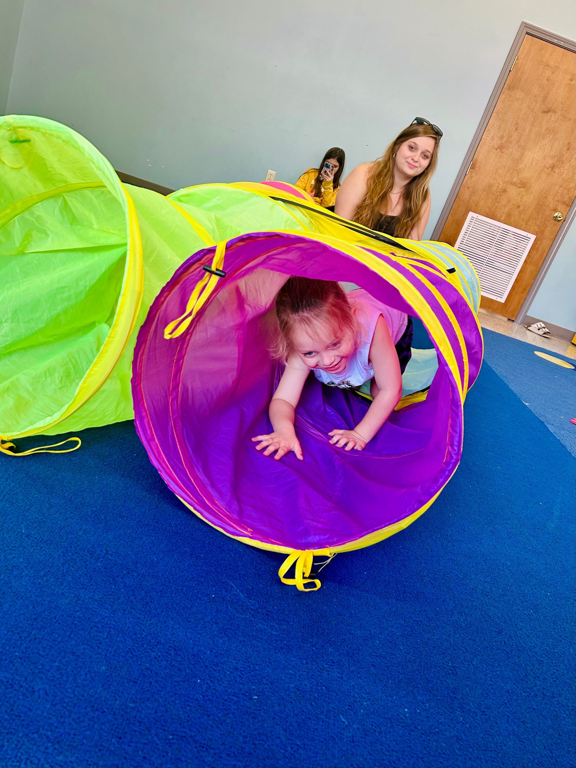 A young girl is doing a handstand on a blue mat in a gym.