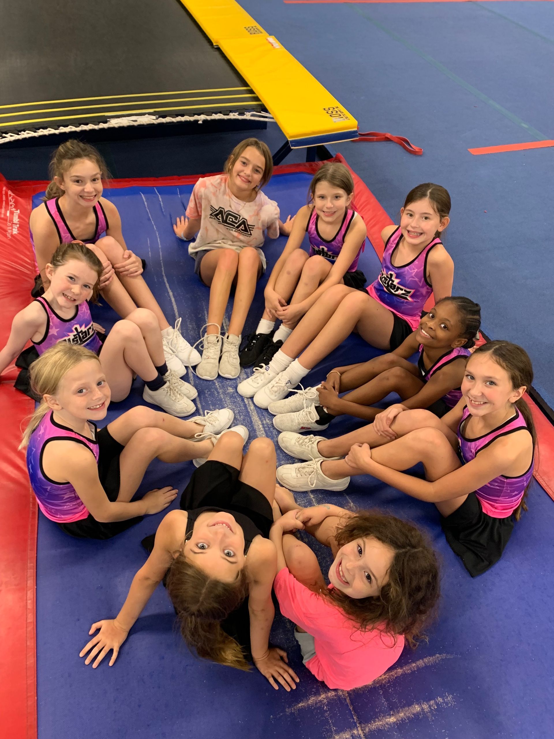 A group of young girls are posing for a picture in a gym.