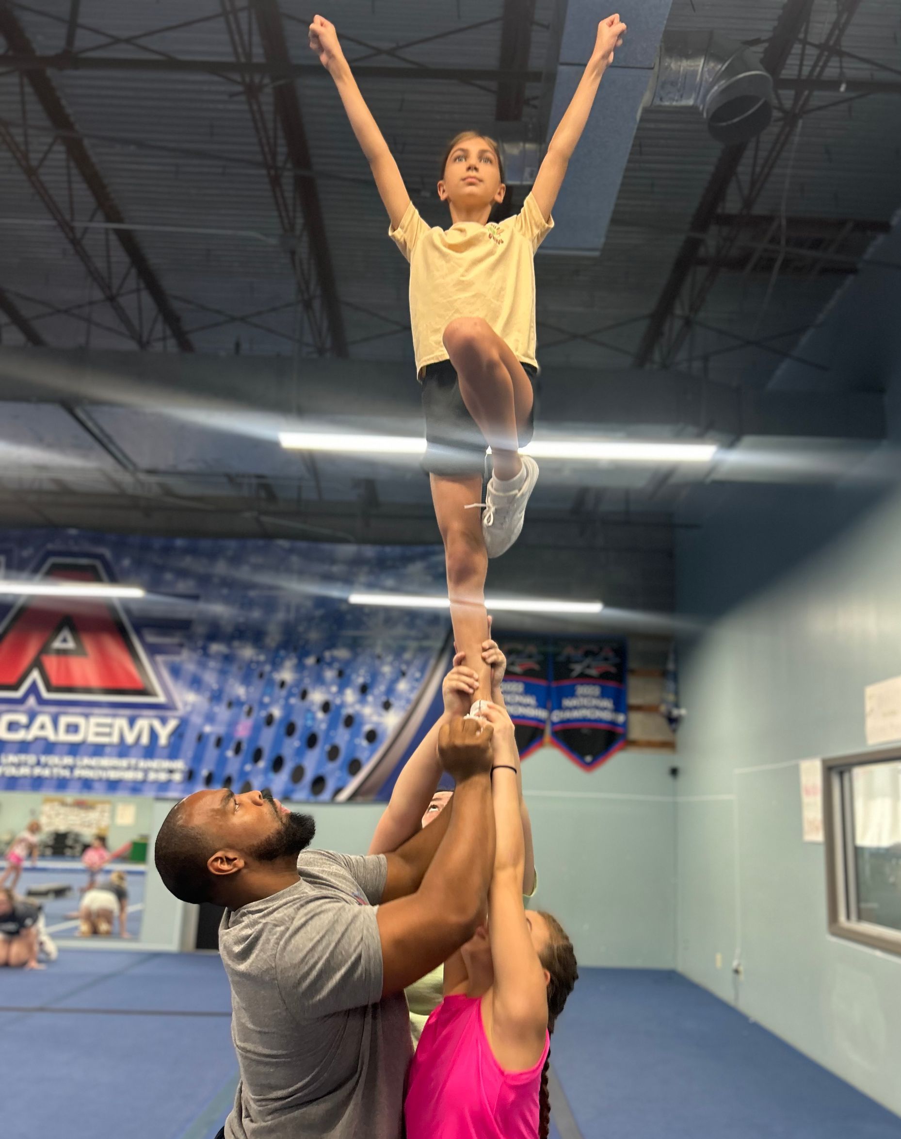 A cheerleader is being lifted in the air by two men