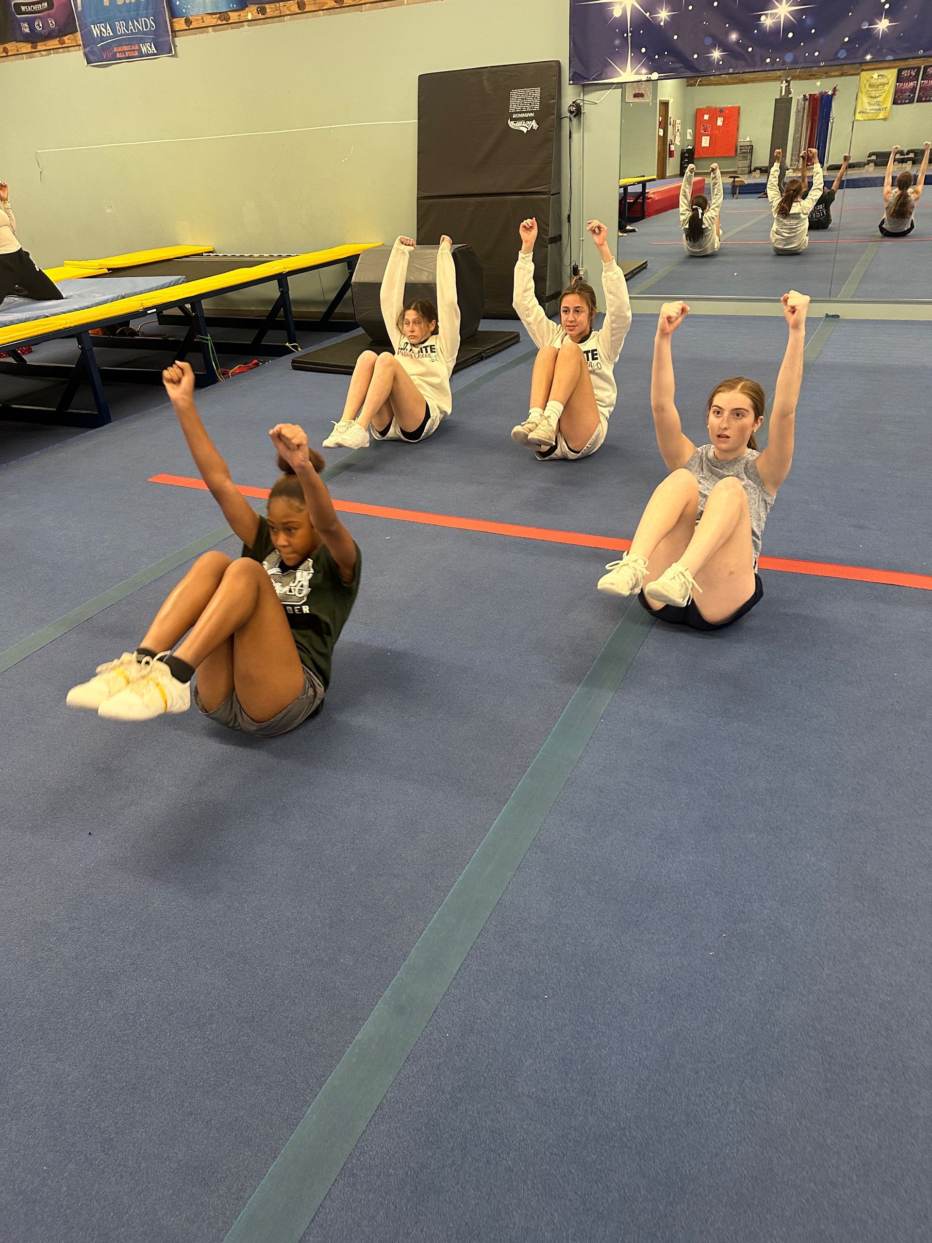 A group of girls are doing sit ups in a gym