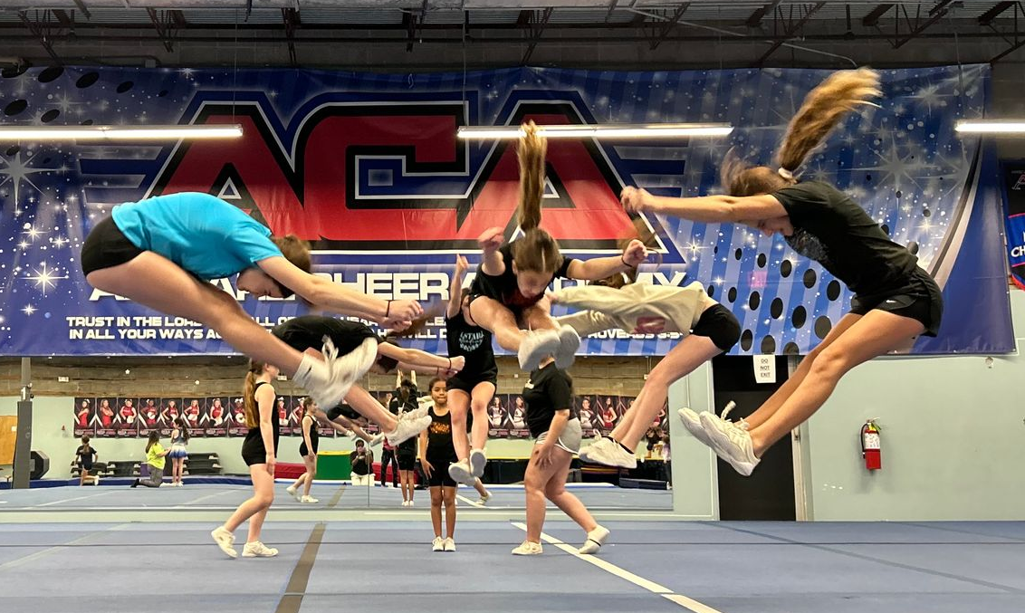 Two young girls are standing on a balance beam in a gym.