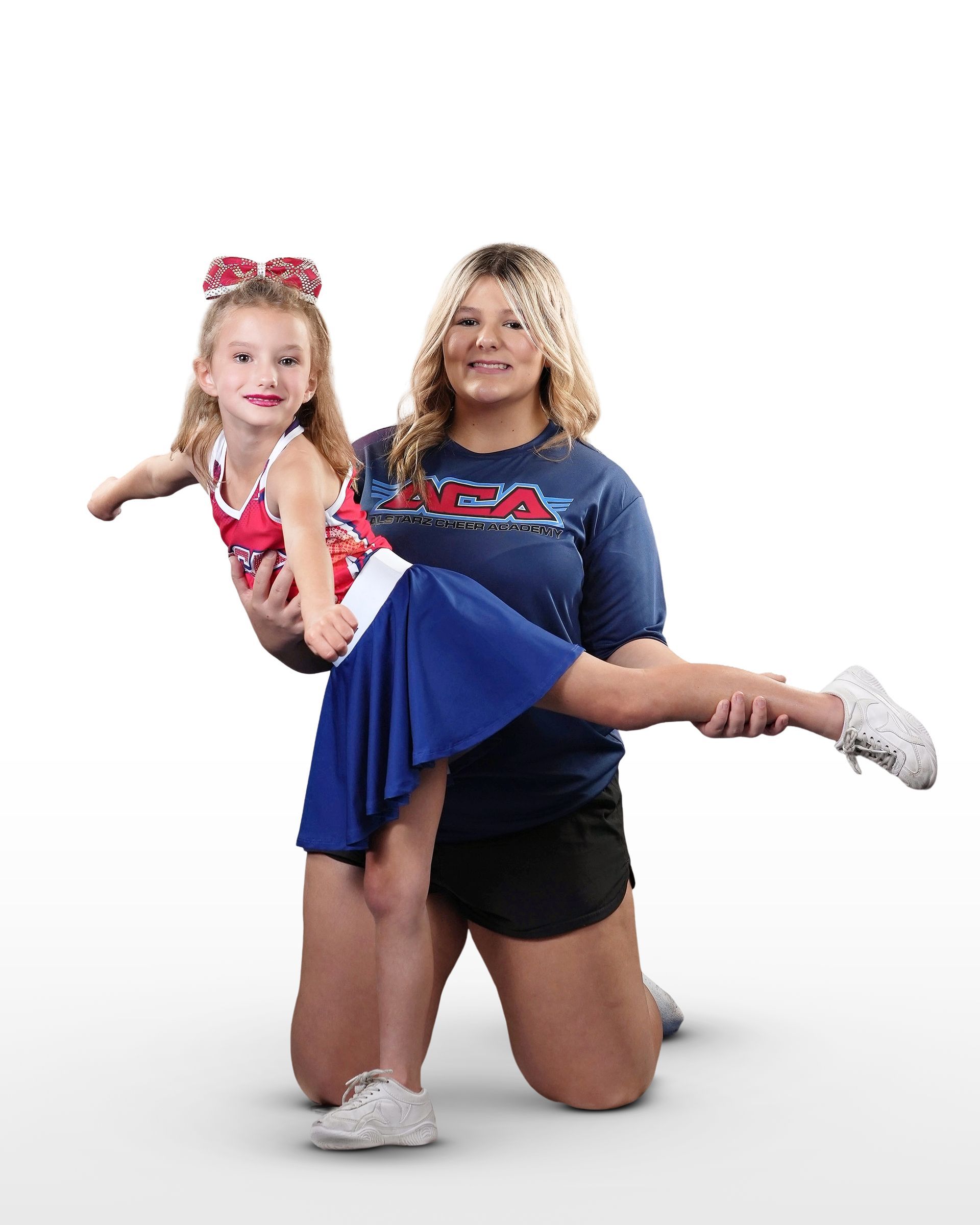 A woman is kneeling down holding a little girl in her arms.