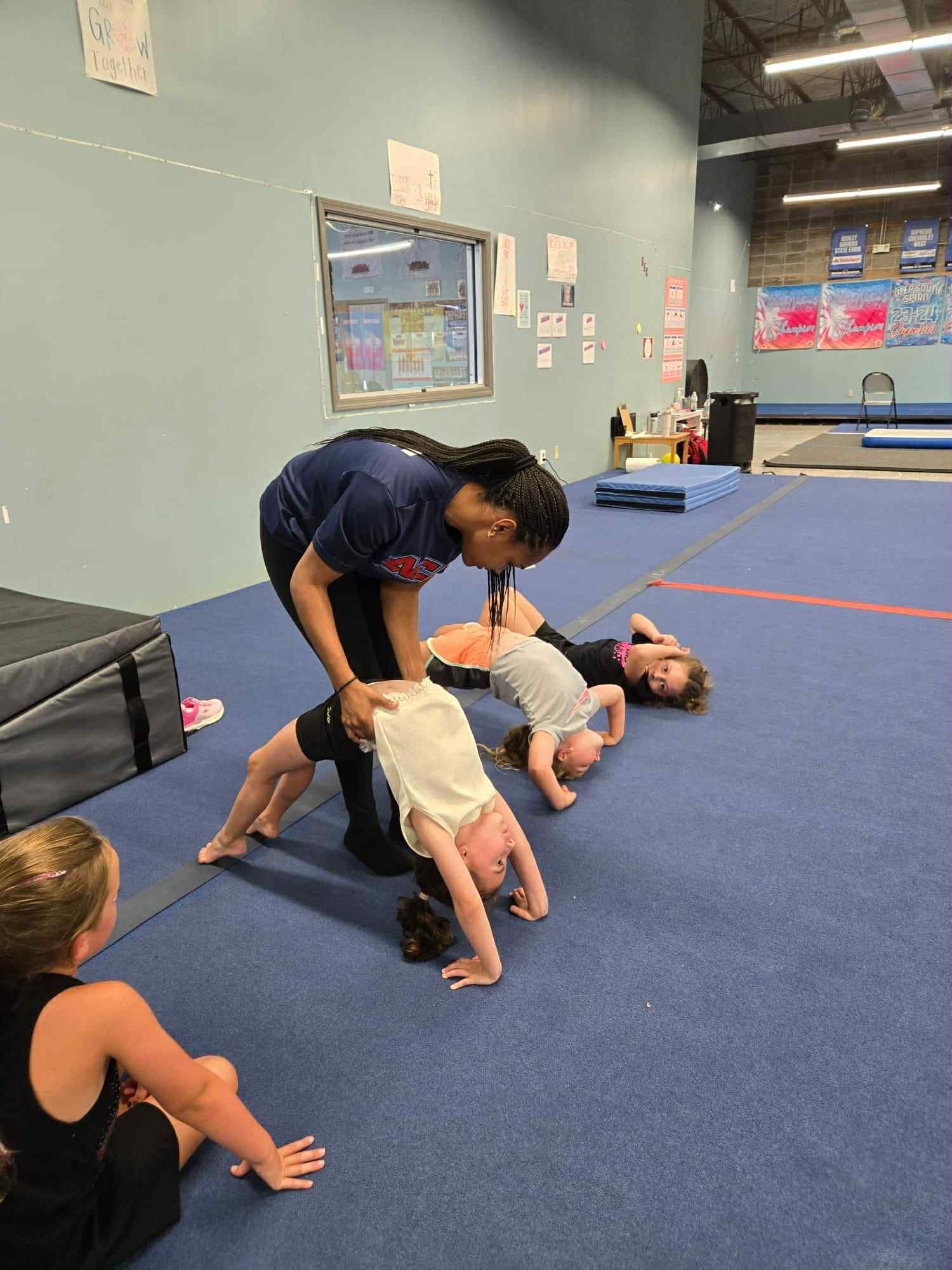 A girl is being lifted in the air by two other girls in a gym.