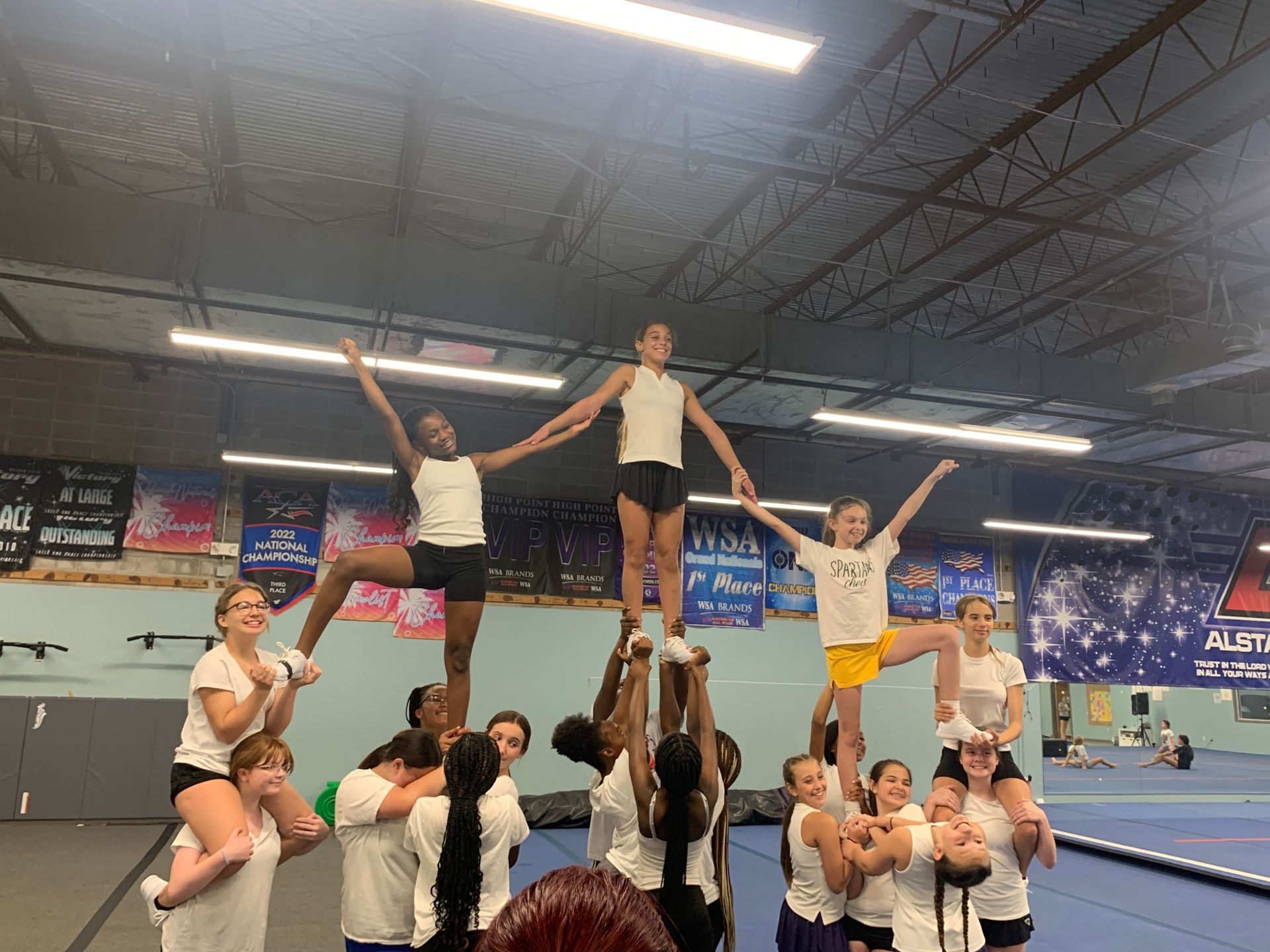 A group of cheerleaders are doing a pyramid in a gym.
