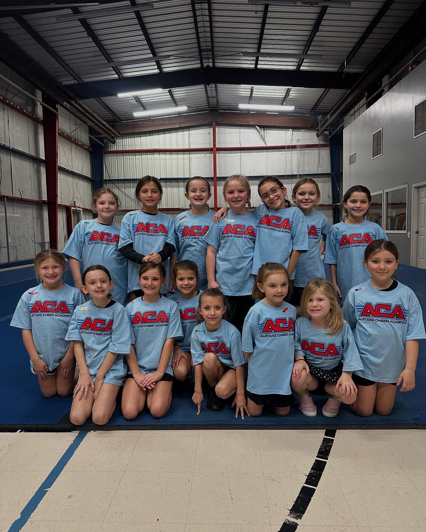 A group of young girls are posing for a picture in a gym.