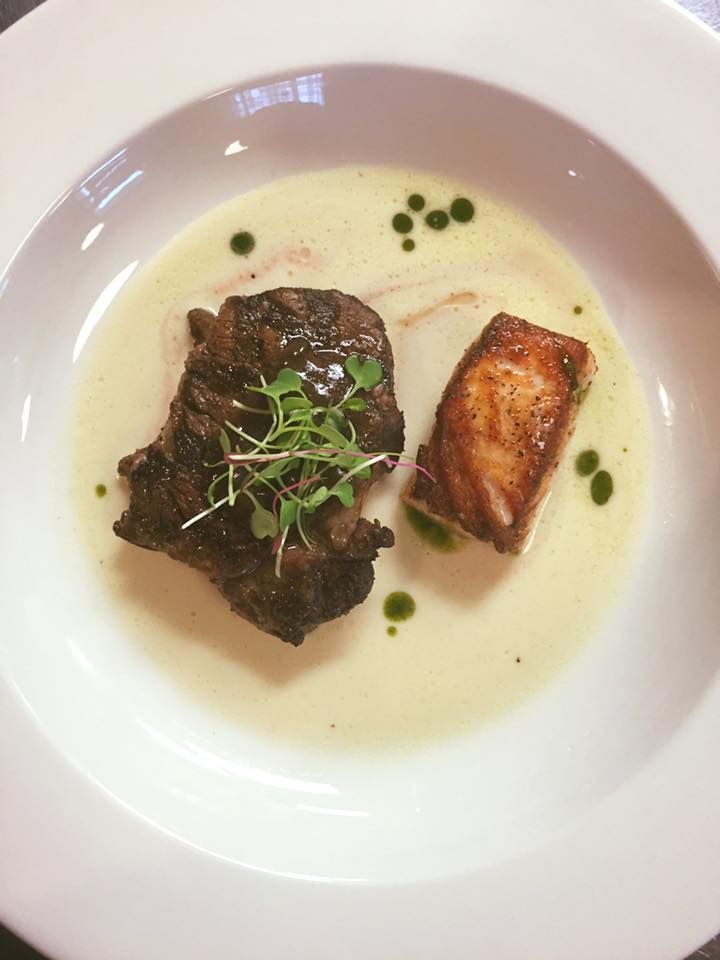 A white plate topped with a piece of meat and sauce.