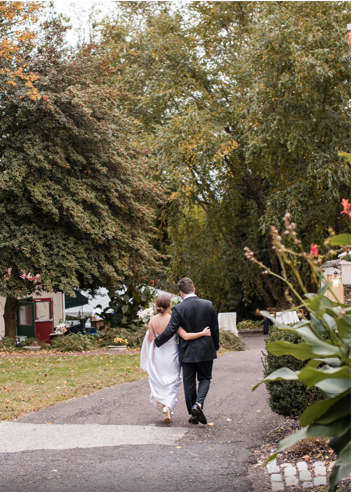 A bride and groom are walking down a path.